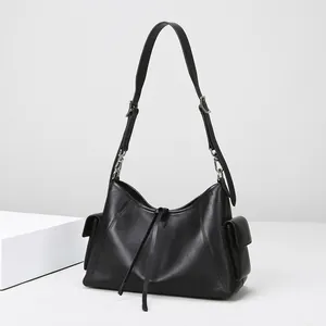 Detalle del bolso tote negro con textura de cuero, cordón ajustable y bolsillo lateral
