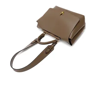 Detailed close-up of dark brown leather handbag with golden twist lock and adjustable strap