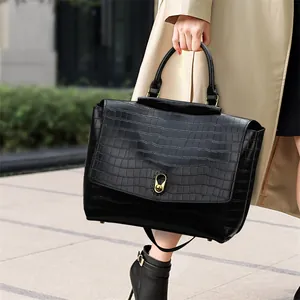 Close-up of black crocodile pattern leather tote bag with elegant gold metal buckle