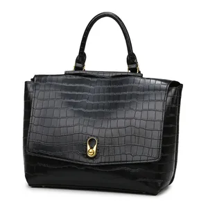 Detailed view of crocodile embossed leather handbag with golden round ball clasp