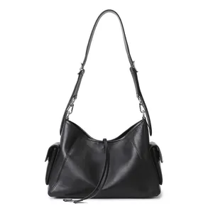 Detalle del bolso tote negro con hebillas plateadas, bolsillos laterales y textura de cuero