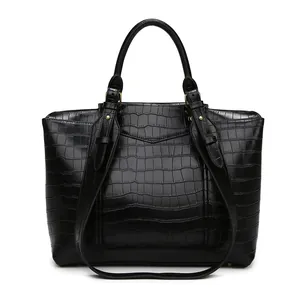 Close-up of black crocodile embossed leather texture with gold hardware on tote bag