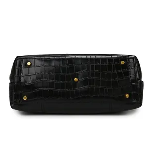 Detail of black crocodile embossed leather handbag base with gold protective metal feet