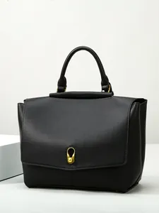 Elegant black faux leather tote bag with gold teardrop lock on white geometric stand