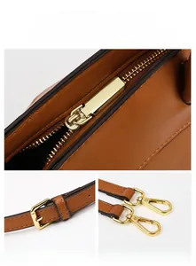 Detail view of brown leather bag with golden hardware zippers and adjustable strap hooks