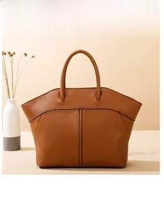 Close-up of brown leather wing tote bag with dual top handles and stitching detail