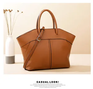 Detailed view of a brown leather tote bag with stitch textures and a golden buckle strap