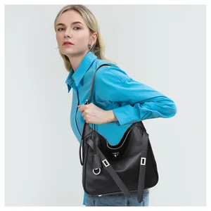 Fashionable black leather hobo bag with silver metal buckles on a blue shirt model