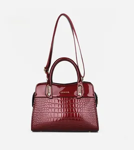 Detail der roten Tragetasche mit Krokoprägung, goldenem Logo und Schultergurt