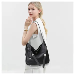 Detail of black leather hobo bag featuring silver square hardware and decorative side straps