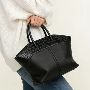 Close-up of black wing tote bag with crocodile texture detail and smooth leather finish