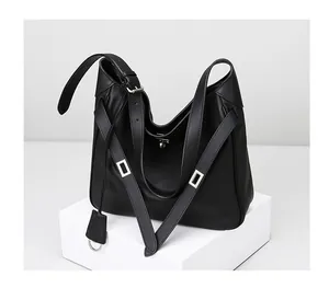 Detail of black leather shoulder bag showing adjustable strap and silver metal rotary lock