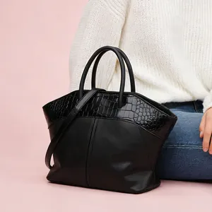 Detail of black tote bag with croc-embossed texture and round handles for office style