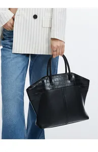 Detail of large black wing-style tote bag with crocodile texture and shoulder straps