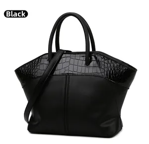 Detail of black trapezoid tote bag showing contrast of crocodile pattern and smooth leather