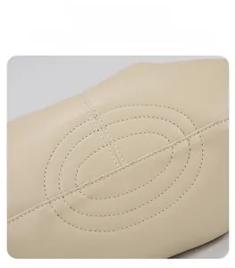 Gros plan des coutures renforcées sur le fond du sac en cuir souple beige clair