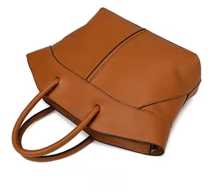 Detailed flat lay of a large brown leather tote bag with fine stitching and dual handles