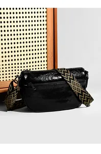 Détail macro du sac en cuir froissé noir avec bandoulière géométrique et poche zippée