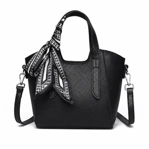 Dettaglio borsa in pelle nera con foulard decorativo in seta a motivo pied de poule