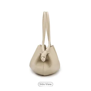 Vue latérale du sac seau minimaliste en cuir beige avec détail de poignée nouée