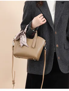 Sac seau en cuir marron avec foulard en soie et bandoulière porté par un mannequin