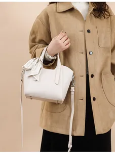 Gros plan du sac seau en cuir beige avec texture litchi et décoration foulard en soie