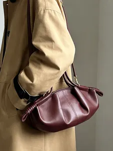 Détail du sac nuage en cuir souple bordeaux avec plis et nœuds décoratifs sur la bandoulière