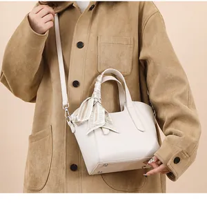 Détail d'un sac seau en cuir beige avec un foulard en soie élégant sur la poignée