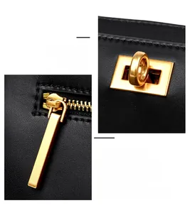 Detail of premium black grained leather handbag with polished gold-tone metal lock and zipper