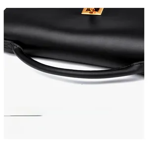 Detail of black leather handbag featuring golden metal twist lock and smooth texture