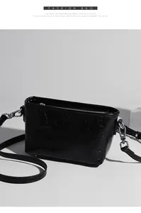 Macro shot of black cracked leather crossbody bag with silver hardware and zipper detail