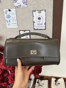 Detail view of a dark brown leather handbag with a wide top handle in a vintage setting