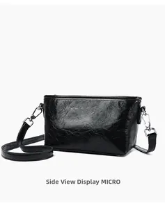 Slight side view of black crossbody bag featuring glossy cracked texture and silver hardware