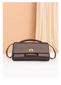 Detailed view of dark brown leather handbag with gold rectangular metal twist lock closure