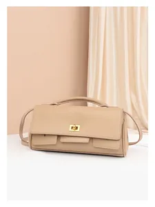 Detail of beige leather crossbody bag with golden rectangular clasp and decorative pockets