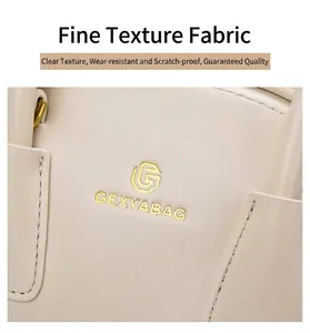 Macro-opname van beige leren handtas met fijne stiksels en metalen logo-details op de tas