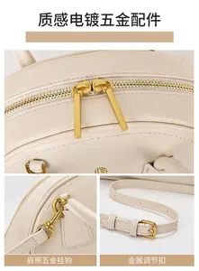 Detailopname van beige handtas met goudkleurige ritsen en metalen schouderhaken