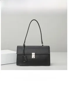 Detail view of black minimalist shoulder bag with silver square buckle and smooth matte finish