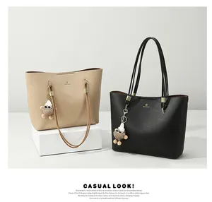 Macro shot of grainy leather texture on beige and black large tote bags with plush charm