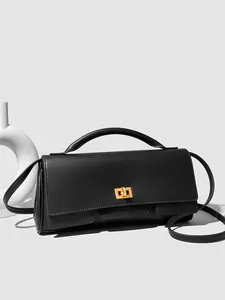 Minimalist black rectangular crossbody bag with golden clasp on a light grey background