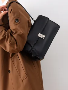 Detailed view of black faux leather shoulder bag with silver clasp on a model