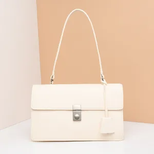 Detail view of cream rectangle shoulder bag with matte leather finish and metal push lock