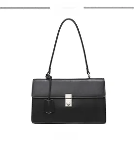 Front view of black minimalist shoulder bag with silver clasp and refined side tag