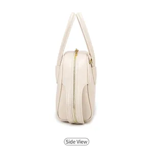 Detail van de beige handtas met de zijstructuur, gouden rits en metalen D-ringbeslag
