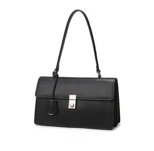 Detail view of black minimalist shoulder bag with silver round metal buckle closure