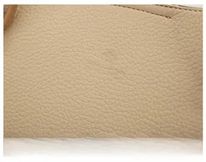 Macro shot of beige lychee grain leather texture with gold embossed GEXYABAG logo