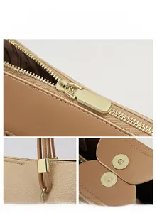 Detail view of beige leather tote with golden zippers, magnetic clasp and ring connectors