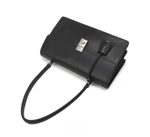 Close-up of minimalist black leather shoulder bag featuring a silver rectangular metal clasp