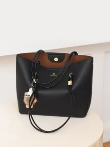 Detail of black pebbled leather tote bag with brown lining and plush bear charm