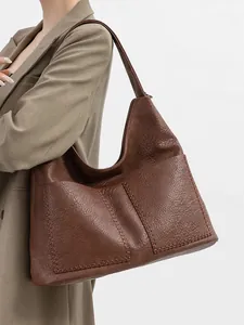 Detail of vintage brown tote bag featuring decorative whipstitch and soft leather texture